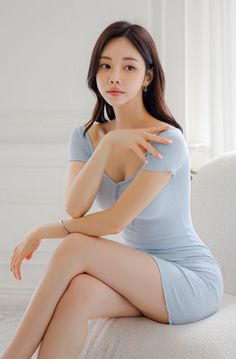 Woman in a light blue dress sitting indoors with soft lighting