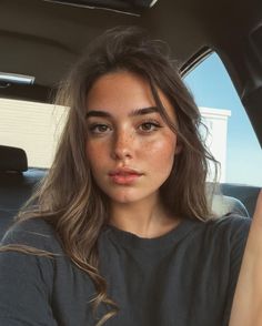 Woman with freckles and long brown hair in a car interior