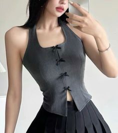 Woman in a gray halter top and black pleated skirt posing indoors