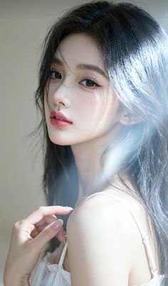 Woman with long black hair and a white top looking over her shoulder