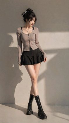 Woman in a black pleated skirt and long sleeve top with black boots