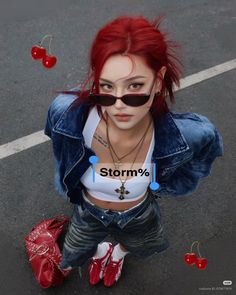 Woman with red hair and sunglasses wearing a denim jacket and crop top