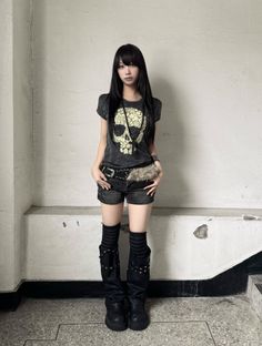 Woman with long black hair wearing a skull t-shirt and denim shorts indoors