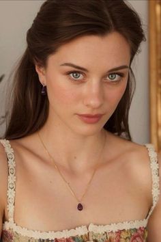 Woman with long brown hair and blue eyes wearing a top with lace trim and jewelry