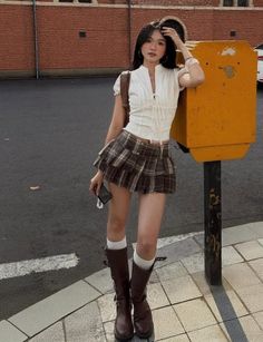 Woman in a plaid skirt and white top standing on a street