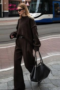 Woman in a brown sweater and wide leg pants walking on a street