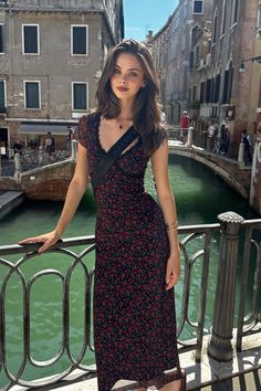 Woman in a floral dress posing on a bridge over a canal in a European city