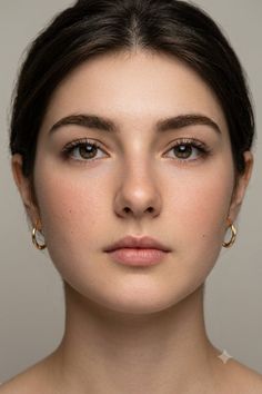 Close up portrait of a woman with dark hair and gold hoop earrings