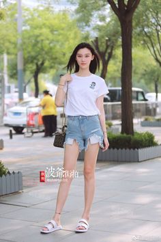 Woman in denim shorts and a white t-shirt standing on a street
