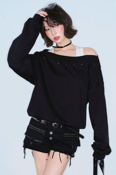 Woman with short hair wearing an off-shoulder top and black shorts