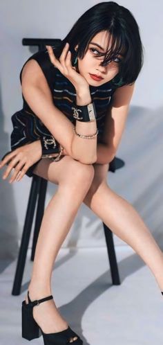 Woman with short black hair wearing a sleeveless top and high heels, sitting indoors