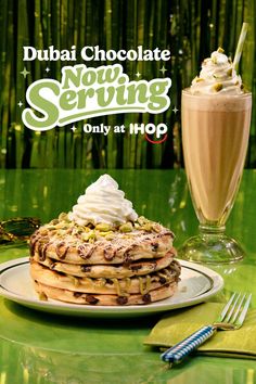 Stack of pancakes with whipped cream and pistachios next to a milkshake