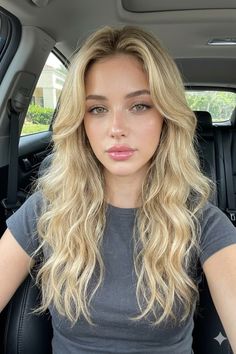 Woman with long blonde wavy hair and green eyes in a car