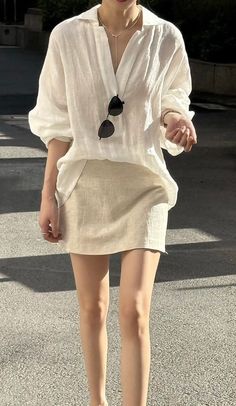 Person in a white shirt and mini skirt with sunglasses hanging from the collar