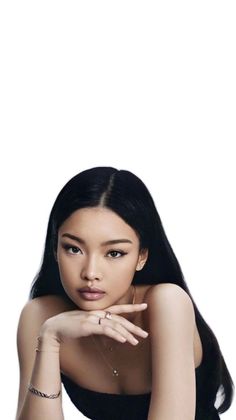 Woman with long black hair and jewelry posing against a white background