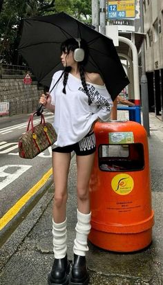 Woman with twin braids, headphones, and an umbrella on a street