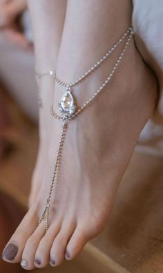 A close up of a foot wearing an anklet and toe ring with brown nail polish