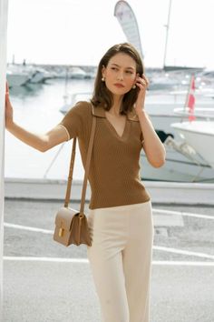 Woman in a brown top and white pants at a marina during the day