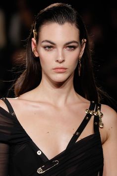 Woman with long hair and gold jewelry wearing a black dress