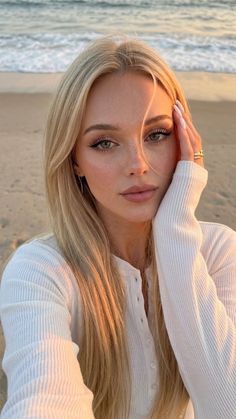 Blonde woman with long hair and freckles on a beach at golden hour