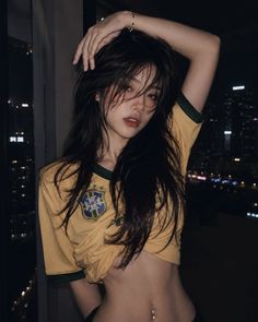 Woman in a yellow shirt with exposed midriff and belly button piercing at night