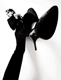 Woman in a black suit and high heels in a dramatic low-angle shot