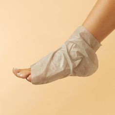 Foot wearing a white foot mask with toes showing a white pedicure