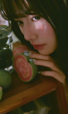 Woman with long hair and freckles holding a sliced guava