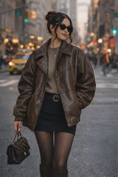 Woman in a brown leather jacket and mini skirt walking on a city street