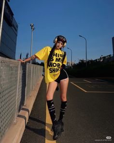 Woman in a yellow t-shirt and black shorts with headphones on a street