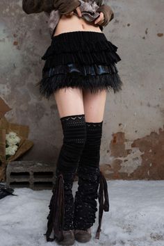 Person in a black ruffled skirt with feather trim and leg warmers, exposing midriff