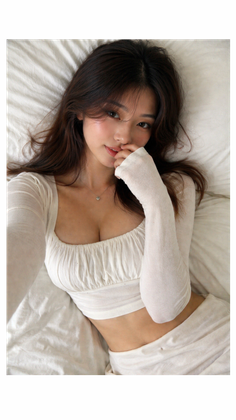 Woman with long hair in a white top lying on a bed