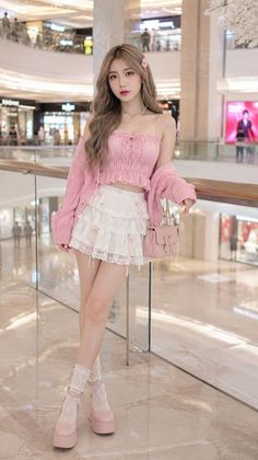 Woman in a pink top and white lace skirt posing in a shopping mall