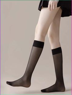 Person wearing black sheer knee-high socks and a short skirt