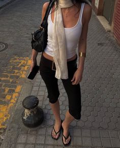 Person in a white tank top and black capri pants on a street at golden hour