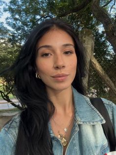 Woman with long black hair and a denim jacket outdoors