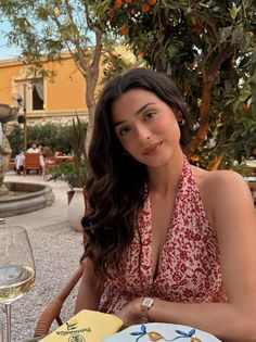 Woman with long dark hair wearing a halter top at an outdoor restaurant