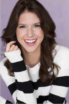 Woman with long brown hair wearing a striped sweater, smiling at the camera