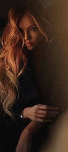 Woman with long blonde hair in a dark, softly lit portrait