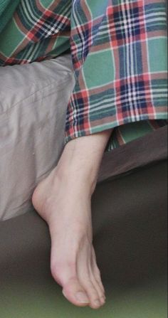 Bare foot resting on a surface with plaid pants visible