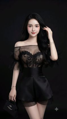 Woman with long black hair wearing a sheer lace top and black shorts