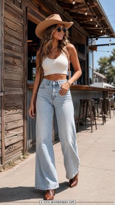 Woman in a cowboy hat, crop top, and wide leg jeans outdoors