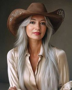 Woman with long silver hair wearing a cowboy hat and satin shirt
