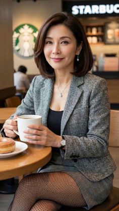 Woman in a gray blazer and fishnet stockings holding a coffee mug in a coffee shop
