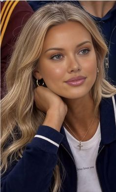 Blonde woman with long hair wearing a navy jacket and cross necklace