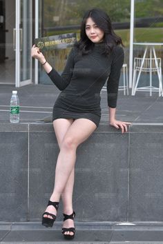 Woman in a black dress and heels posing outdoors
