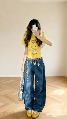 Person in a yellow t-shirt and plaid pants taking a mirror selfie