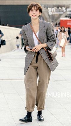 Woman with short hair wearing a blazer and wide-leg pants on a street
