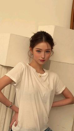 Woman with blue eyes and an updo wearing a white t-shirt and gold necklace