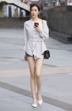 Woman in a striped top and denim shorts walking on a street